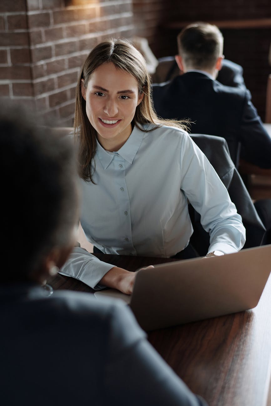 woman in light blue dress shirt using a laptop